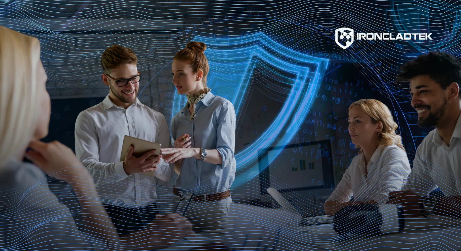 The image represents the title of the blog, The Human Element: Why Your Biggest Security Risk Isn’t Your Technology. There is a group of people in business casual clothes at an office, looking at tablets and laptops. In the background, a blue digital shield is visible.